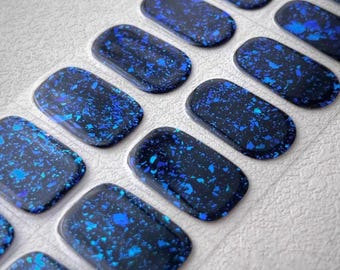 May include: A sheet of blue and black nail polish wraps with a glittery finish. The wraps are arranged in rows on a white surface. The text "Nailsera" is visible at the bottom of the image.