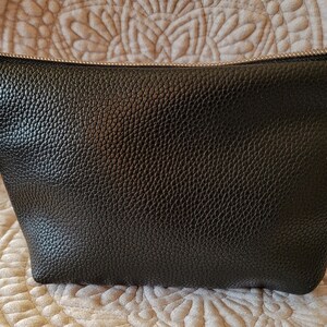 May include: Black zippered pouch with a silver zipper and a red beaded charm attached to the zipper pull.