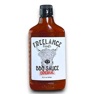 May include: A glass bottle of barbecue sauce with a white label. The label features a black and white illustration of a Highland cow and the text "FREELANCE Foods BBQ SAUCE ORIGINAL 12.5 FL OZ (369 ML)"
