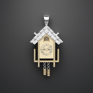 Può includere: Un ciondolo a forma di orologio a cucù in oro e argento con un quadrante bianco e indici orari romani neri. L'orologio ha una catena con due pesi dorati.