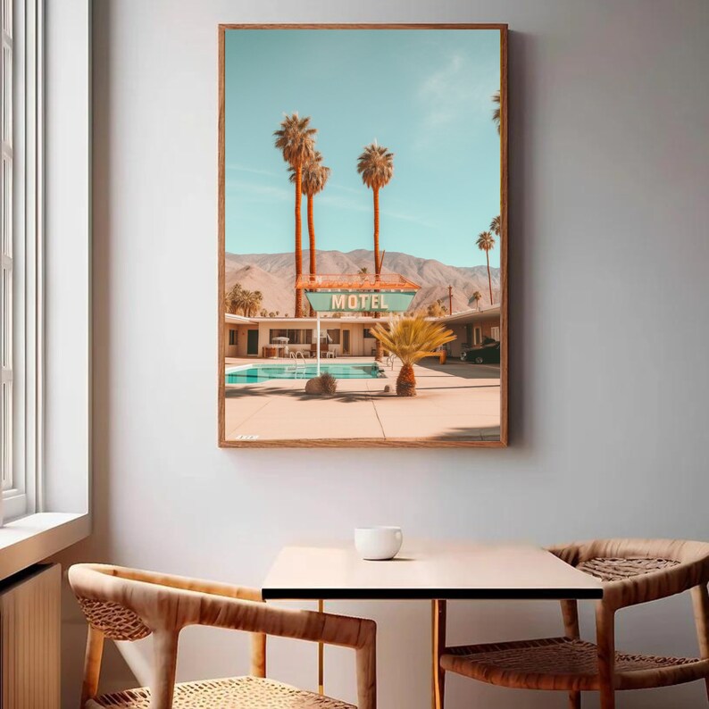 Op de afbeelding: Een rechthoekige wandkunstprint met een woestijnmotel, een turquoise zwembad, hoge palmbomen en een bord met de witte tekst MOTEL. Op de achtergrond zijn droge bergen te zien onder een heldere, lichtblauwe lucht.