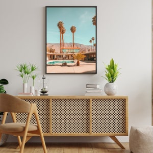 Op de afbeelding: Een ingelijste wandkunstprint met een woestijnmotelsc&egrave;ne met een zwembad, palmbomen en bergen op de achtergrond. Het bord boven het zwembadgedeelte toont duidelijk het woord MOTEL in dikke, donkere letters tegen een lichte achtergrond.