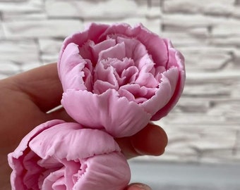 May include: Two pink fabric peonies, one on top of the other, held in a hand.