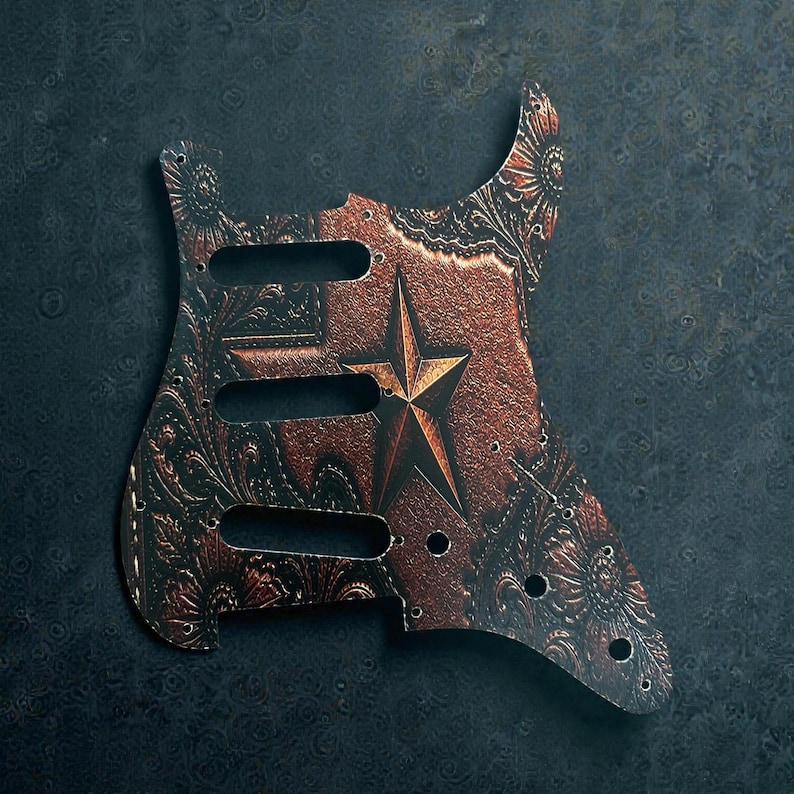 May include: A guitar pickguard with a distressed copper finish and a star design. The pickguard features intricate floral patterns and three pickup cutouts. The star is centered on the pickguard, adding a rustic aesthetic.