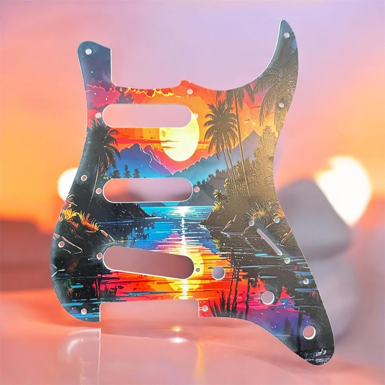 May include: A guitar pickguard featuring a vibrant tropical sunset scene with palm trees, mountains, and a reflective body of water. The pickguard has three pickup cutouts and mounting holes, with a colorful gradient of orange, yellow, blue, and purple.
