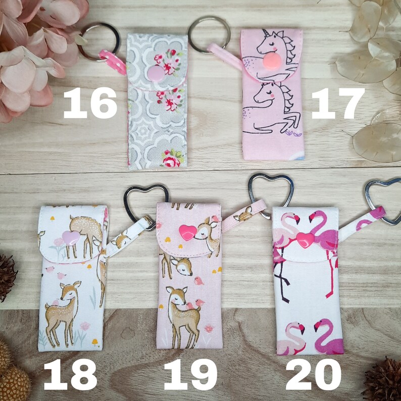 May include: Fabric keyrings with diverse patterns: floral, unicorns, deer, and flamingos. Each keyring features a metal ring and a fabric loop. Numbers 16, 17, 18, 19, and 20 are printed on the image.