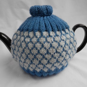 May include: A black teapot with a blue and white knitted tea cosy. The cosy features a diamond pattern and a matching top. The teapot has a curved spout and handle.