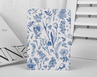 May include: A floral patterned case featuring a botanical design in blue on a cream background. The design includes detailed illustrations of various flowers and foliage, such as tulips and ferns. The case is standing upright.
