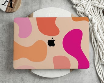 May include: A laptop computer with a colorful abstract design on the case. The design features pink, orange, and red shapes on a beige background. The Apple logo is visible on the case.