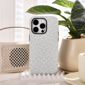 May include: White iPhone case with a gray leopard print design. The case has a raised camera bump and a cutout for the phone's buttons.