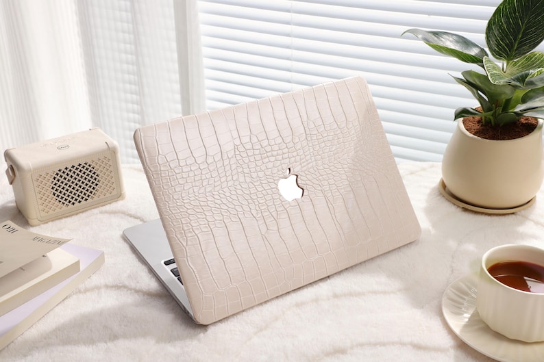 May include: A white laptop computer with a crocodile-embossed leather case. The case has a cut-out for the Apple logo.
