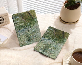 May include: Two rectangular, green and white patterned coasters with a blurred background of a white fuzzy surface, a white radio, a magazine, a potted plant, and a cup of coffee.