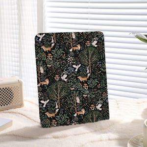 Op de afbeelding: Een zwarte en groene iPad-hoes met een herhalend patroon van vossen, vogels, bomen en bloemen.