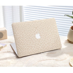 Puede incluir: Un ordenador portátil beige con un diseño de estampado de leopardo en la tapa. El logotipo de Apple es visible en la tapa.