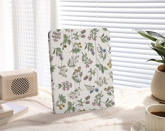 May include: A white iPad case with a floral pattern featuring various types of flowers and leaves in shades of pink, blue, green, and yellow.
