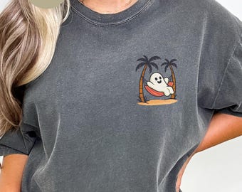 May include: Dark grey t-shirt with a small graphic of a cartoon ghost relaxing in a hammock between two palm trees. The word "Pepper" is printed on a circular label in the upper left corner. The shirt has a relaxed fit.