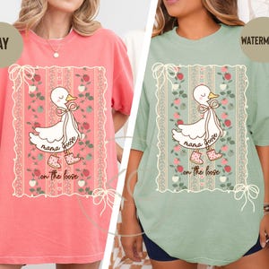 May include: Two oversized t-shirts, one bay and one watermelon, featuring a cartoon goose design. The goose is wearing boots and a bow, with the words "mama goose on the loose" printed below. The design is framed by a floral border.