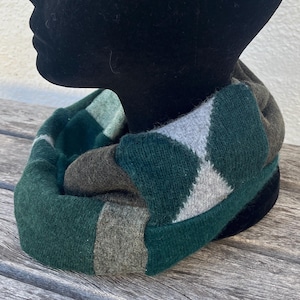 May include: A green, gray, and brown knit infinity scarf with a diamond pattern.