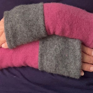 May include: A pair of gray and pink knitted wrist warmers. The warmers are made of a soft, fuzzy material and are perfect for keeping your hands warm in the cold weather.