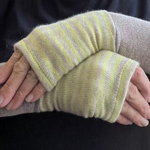 May include: A pair of striped arm warmers in beige and yellow. The arm warmers are made of a soft, knitted fabric.