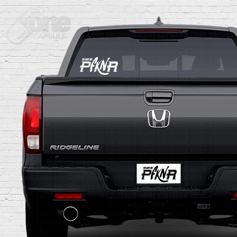 May include: A black pickup truck with a white "YO SOY DE PAKNR" sticker on the back window and a "RIDGELINE" emblem on the tailgate.