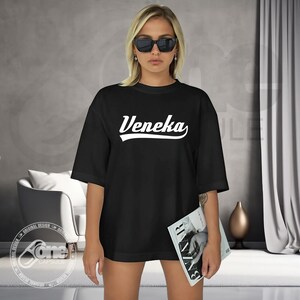 May include: Black oversized t-shirt with white text that reads "Veneka" in a retro baseball font.