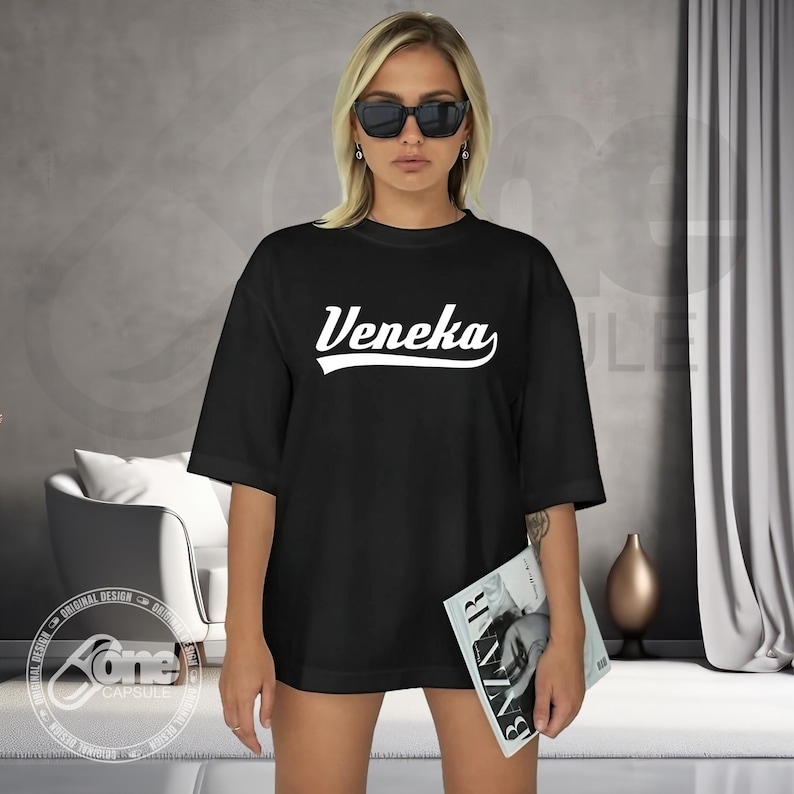 May include: Black oversized t-shirt with white text that reads "Veneka" in a retro baseball font.