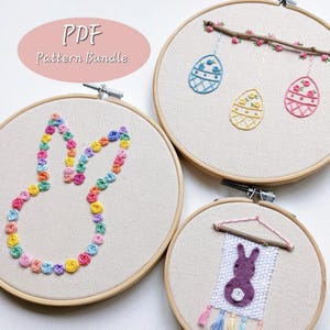 May include: Three embroidery hoop patterns for Easter. The first pattern is a bunny made of colorful flowers. The second pattern is a branch with three hanging eggs decorated with flowers. The third pattern is a banner with a purple bunny and tassels.