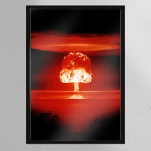 Op de afbeelding: Een zwart-wit ingelijste foto van een paddenstoelwolk van een nucleaire explosie. De wolk is fel oranje en rood van kleur en stijgt op in een donkere lucht.