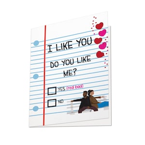May include: A greeting card with a lined paper design. The text reads "I LIKE YOU, DO YOU LIKE ME?" with check boxes for "YES (real bad)" and "NO." Red and pink hearts decorate the right side. A couple is illustrated at the bottom.