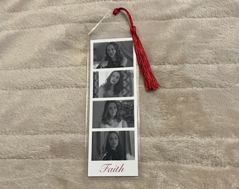 Puede incluir: Marcapáginas transparente con cuatro imágenes en blanco y negro de una mujer. El marcapáginas tiene una borla roja y la palabra "Faith" en cursiva en la parte inferior. El marcapáginas está hecho de plástico transparente.