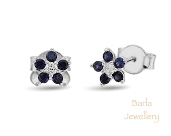 Puede incluir: Un par de pendientes de plata con diseño de flor. La flor tiene cinco zafiros azules y un solo diamante blanco en el centro.