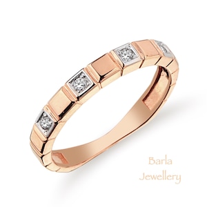 Puede incluir: Un anillo de banda de oro rosa con una fila de pequeños diamantes cuadrados engastados en la banda. Barla Joyería.