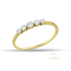 Puede incluir: Un delicado anillo de banda de oro con cinco pequeños diamantes redondos engastados en fila.