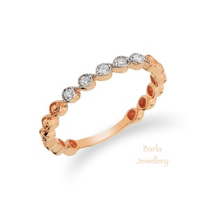 Puede incluir: Un anillo de banda de oro rosa con una fila de pequeños diamantes redondos engastados en el centro de la banda. La banda está texturizada con una serie de pequeños bultos redondeados.