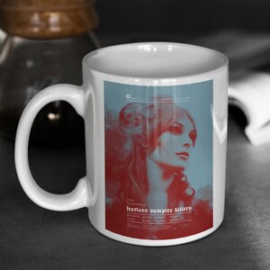 May include: White ceramic mug with a movie poster design for "Fearless Vampire Killers." The poster features a woman's portrait in red and blue hues, with the film's title and cast names at the base. The mug has a curved handle.