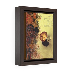 May include: A framed canvas print featuring a colourful abstract background and a portrait of a person with a large eye. The text "COIL presents BLACK LIGHT DISTRICT" is printed in white on a yellow background.