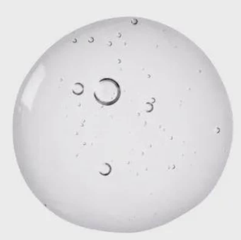 Pu&ograve; includere: Una sostanza trasparente simile a un gel con numerose bolle d'aria sospese al suo interno. Le bolle variano di dimensione, alcune appaiono come piccoli punti e altre come cerchi pi&ugrave; grandi e definiti. Lo sfondo &egrave; grigio chiaro uniforme.