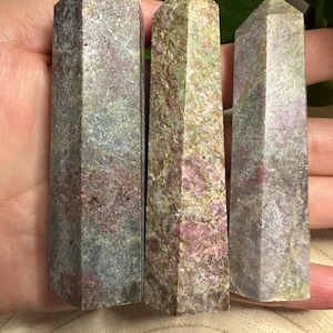 May include: Three grey, green, and pink crystal points with a pointed tip. The points are arranged in a row from left to right.