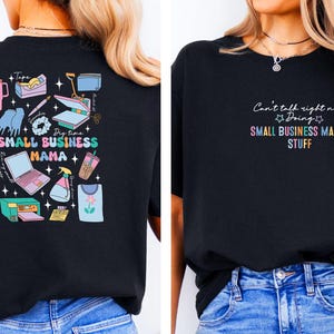 K&ouml;nnte beinhalten: Schwarzes T-Shirt mit einem grafischen Design auf der R&uuml;ckseite, das einen Laptop, Werkzeuge und den Text "Dig time SMALL BUSINESS MAMA" zeigt. Die Vorderseite des Shirts tr&auml;gt den Text "Can't talk right now Doing SMALL BUSINESS MAMA STUFF" in Regenbogenfarben.