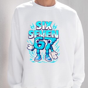 May include: White sweatshirt with a cartoon design. The words "SIX SEVEN" are in blue and white, with the numbers 6 and 7 personified with arms, legs, and shoes. Lightning bolt accents surround the text.