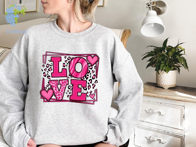 May include: A gray sweatshirt with a pink graphic design that says "LOVE" with leopard print and hearts.