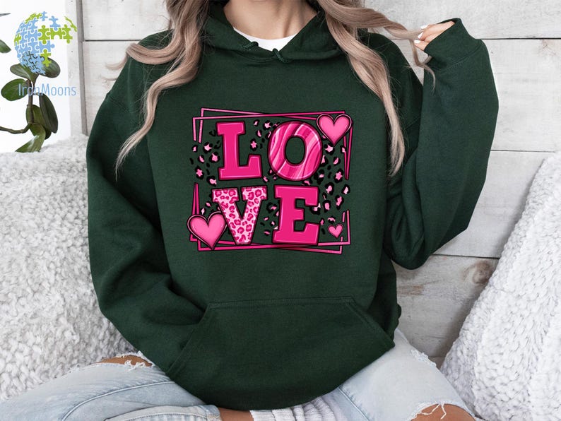 May include: A dark green hoodie with a pink graphic of the word "LOVE" surrounded by hearts and leopard print.