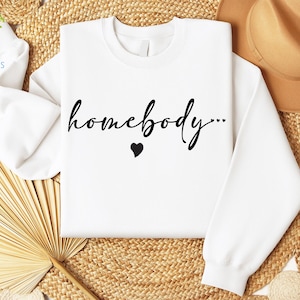 May include: White sweatshirt with the text "homebody..." in black cursive lettering and a small black heart.