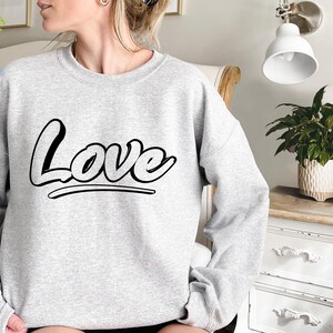May include: A gray sweatshirt with the word "Love" printed in black stylized lettering.