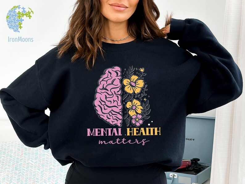 May include: Black sweatshirt with a pink and yellow brain and flowers graphic. The text "Mental Health Matters" is printed below the graphic.