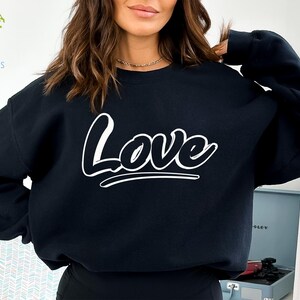May include: A black sweatshirt with the word "Love" printed in white on the front. The word is stylized with a bold, rounded font.