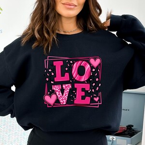 May include: Black sweatshirt with a pink "LOVE" graphic featuring leopard print and hearts.