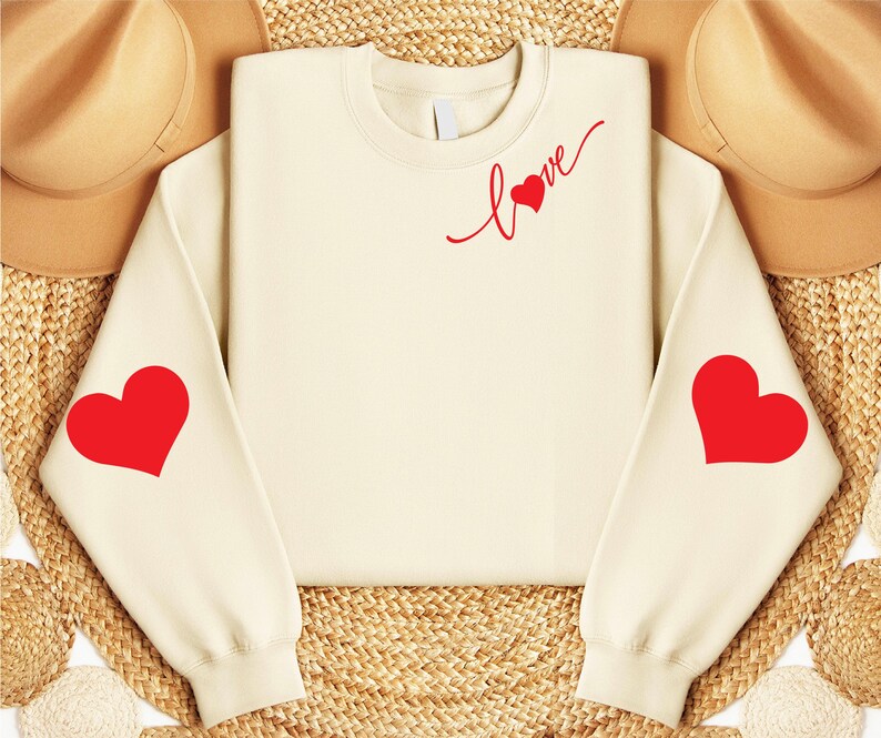 May include: A cream-colored sweatshirt with red hearts on the sleeves and the word "love" with a heart on the front.