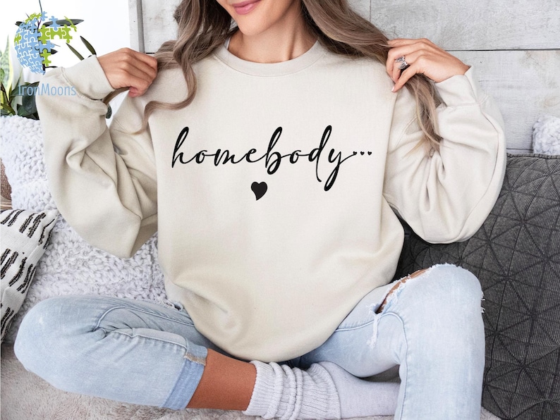 May include: A cream colored sweatshirt with the text "homebody..." in black cursive lettering and a small black heart.